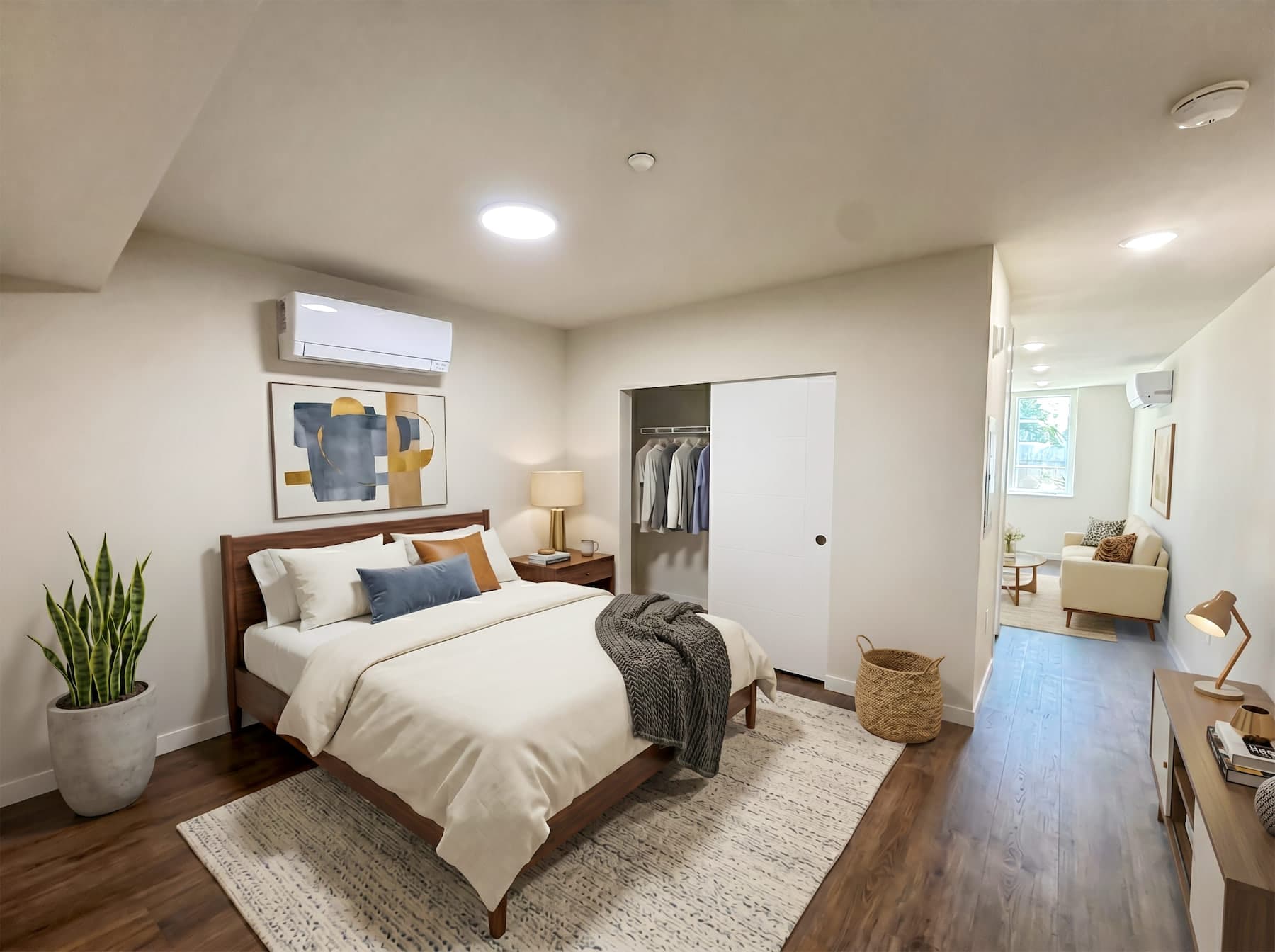 A lamplit bedroom at Thirteen East opening onto the living room, warm wood floors at dusk